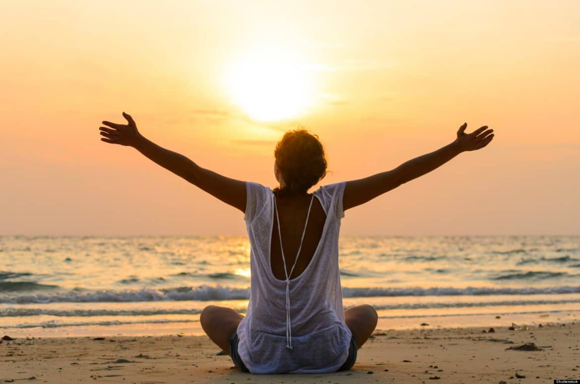 Black Woman Raising Arms on Beach